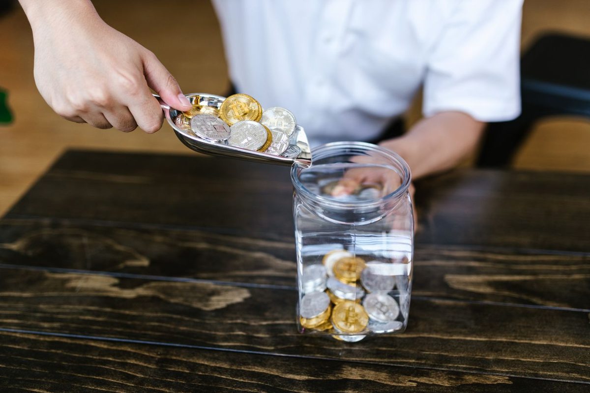 Coins being poured into a glass savings jar