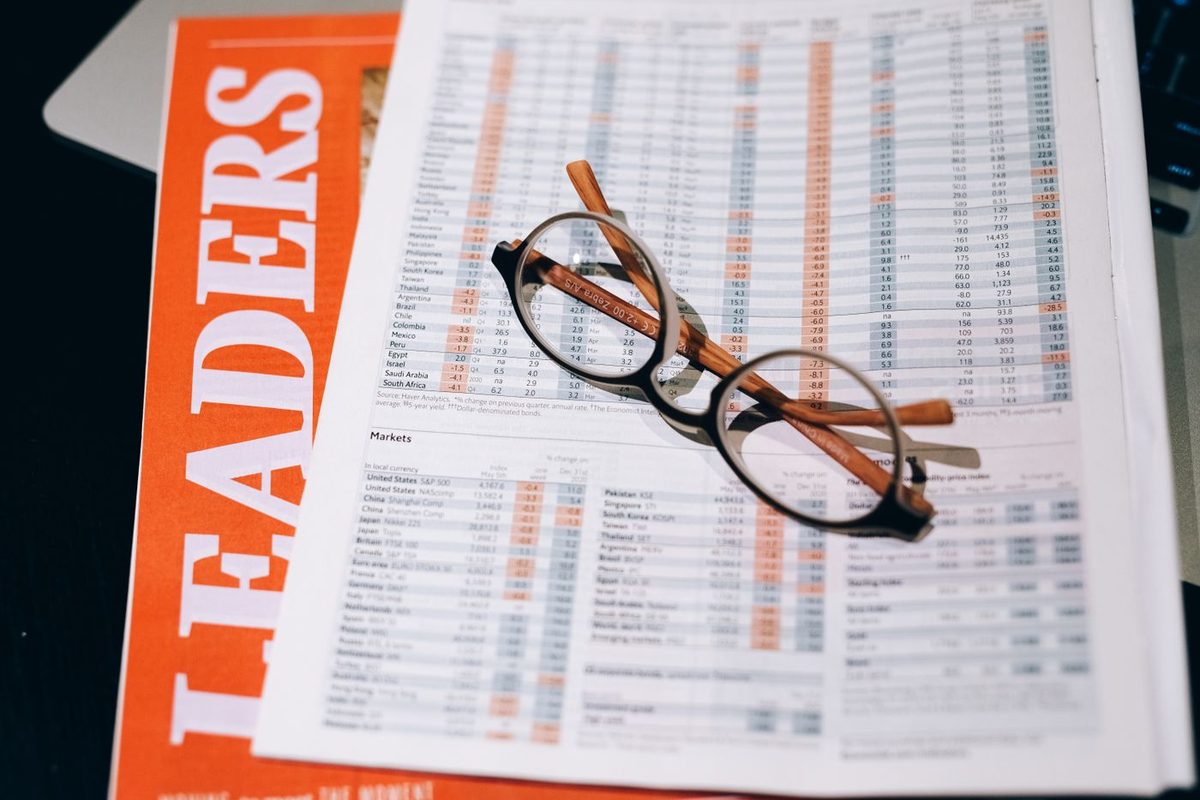 Reading glasses resting on printed pages of global market index tables
