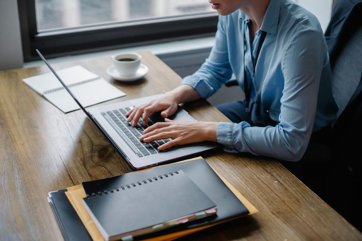 An employee working at a desk in an office, staff lanyard visible