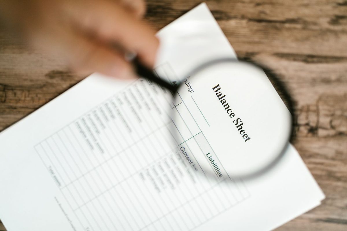 A magnifying glass held over a balance sheet