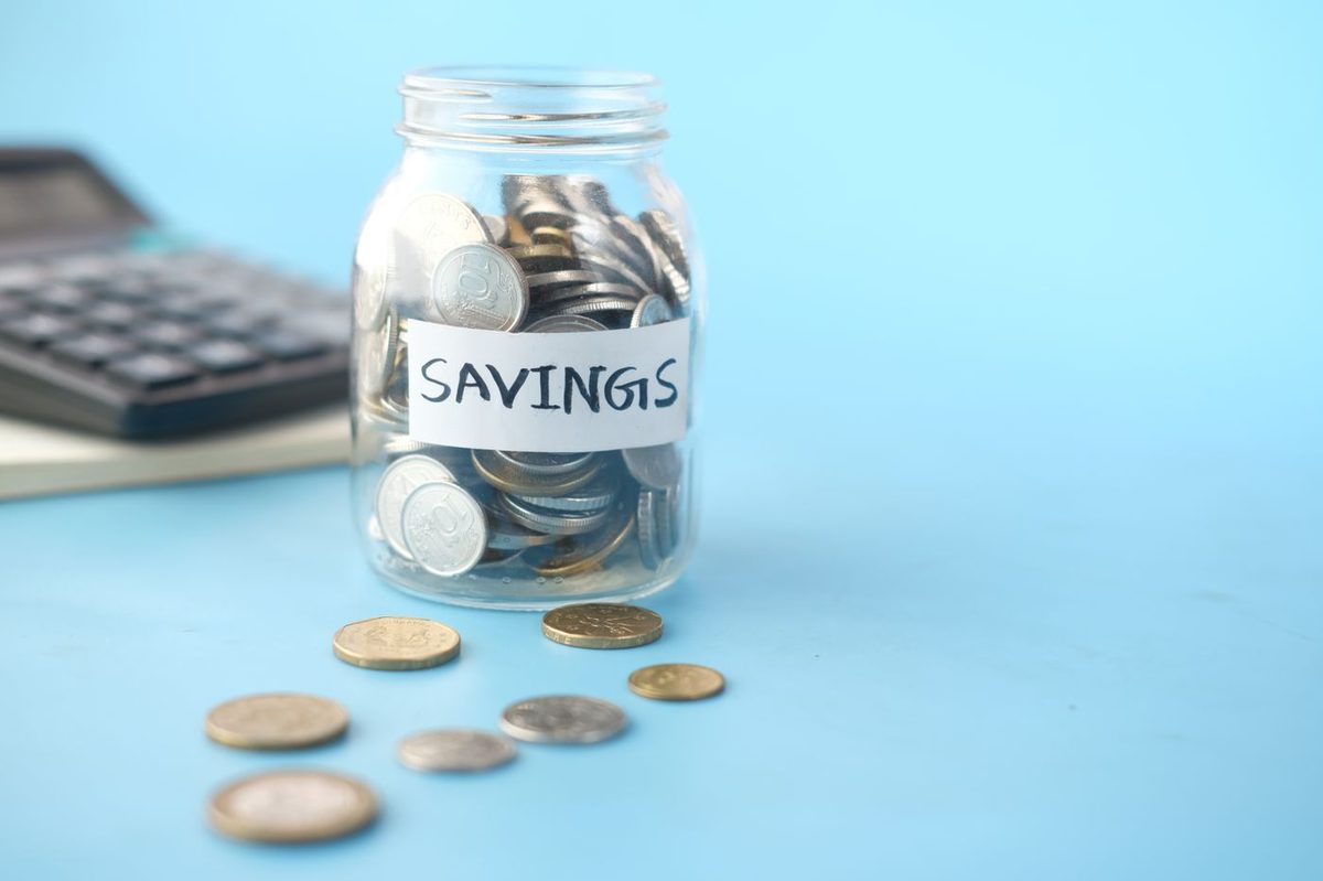 A jar of coins labelled savings beside a calculator