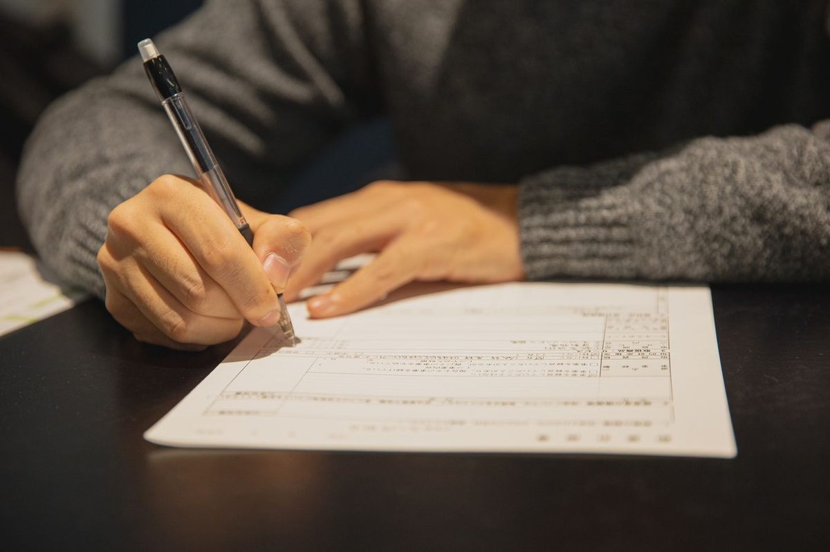 A hand signing a form at a desk