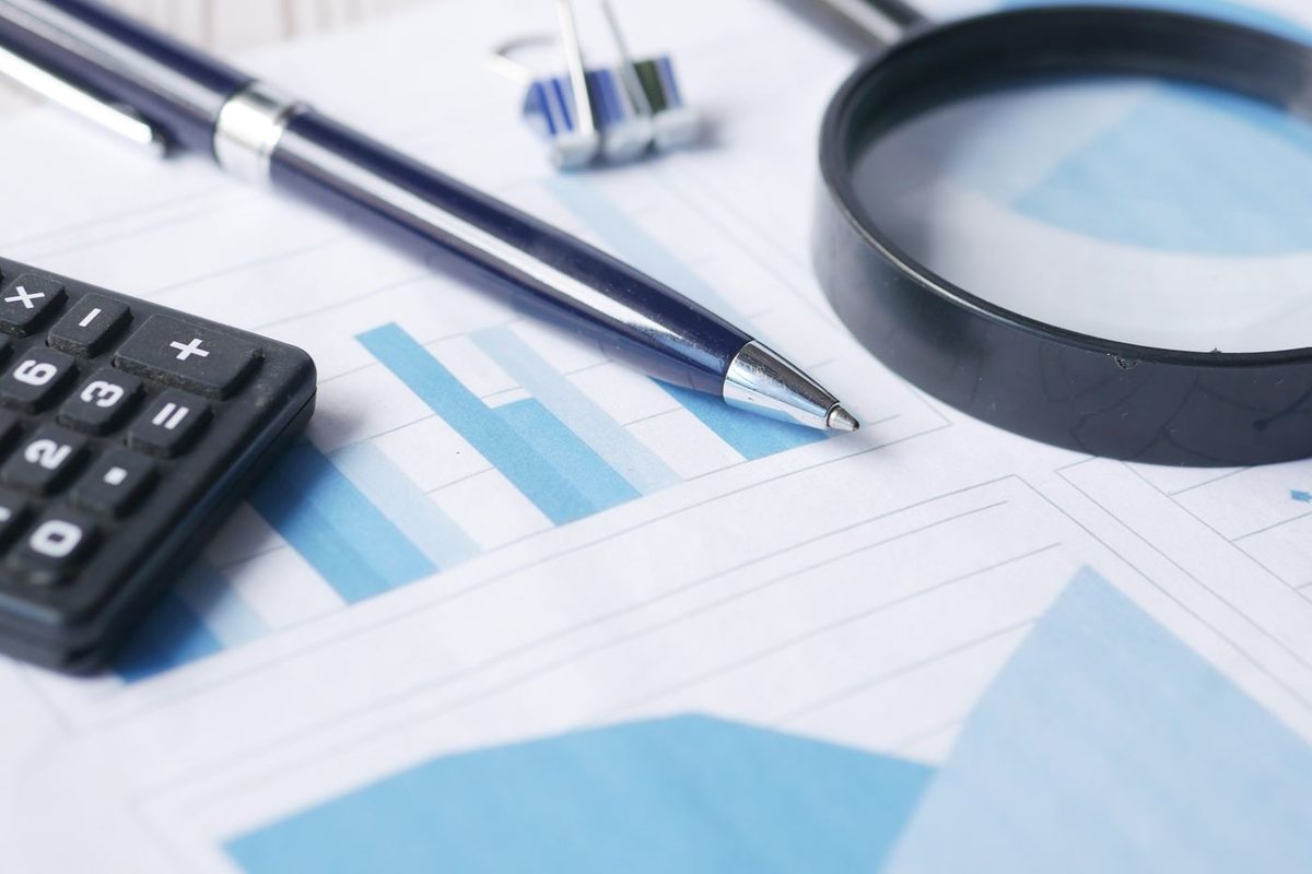A calculator and magnifying glass resting on a financial chart