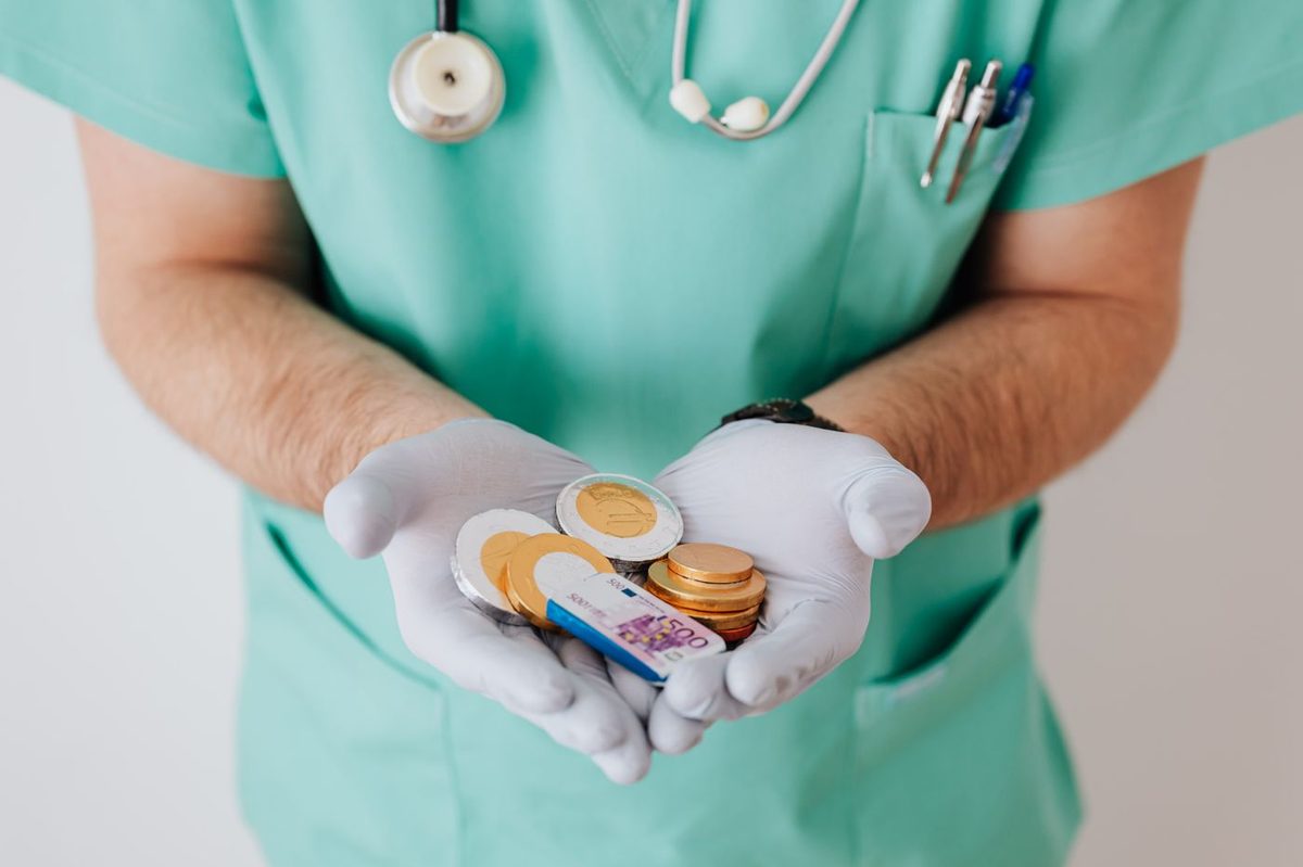 A healthcare worker in scrubs holding a handful of coins
